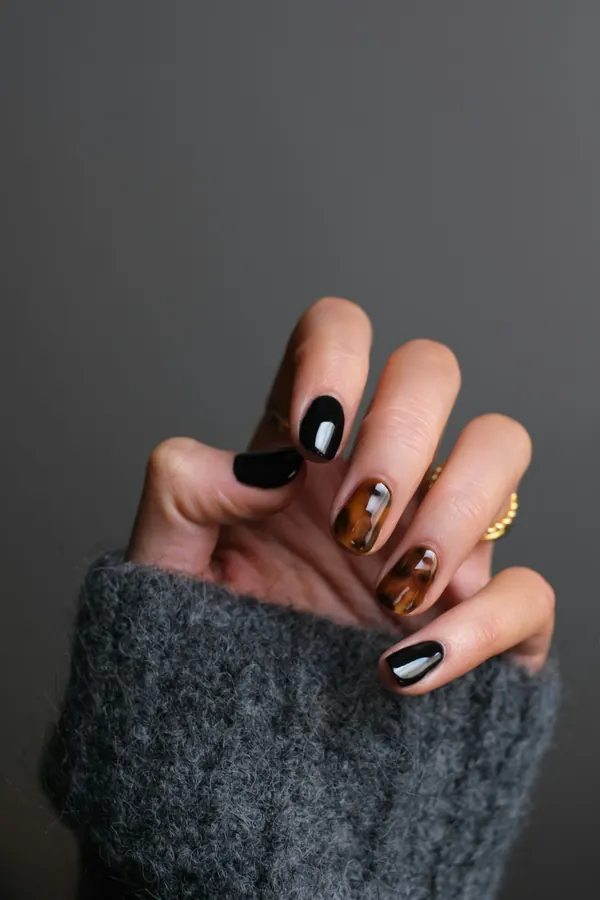 Unhas pretas e em efeito tartaruga com anel dourado