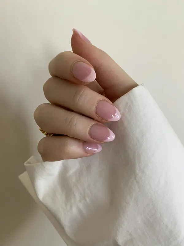 Unhas rosa-claro sobre tecido branco