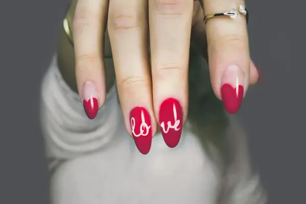 Unhas vermelhas com a palavra love escrita à mão
